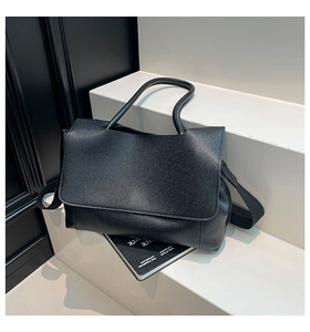 Close-up of minimalist black matte leather tote bag with wide detachable shoulder strap