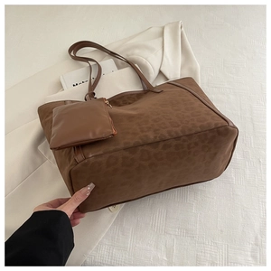 Detail of leopard print tote bag with small matching pouch on premium white fabric background