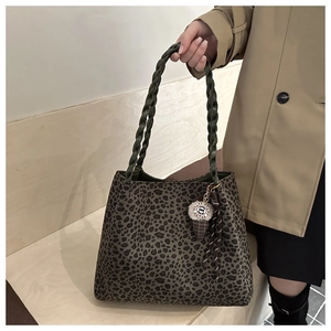 Detail of green leopard print tote with woven handle and plush ice cream charm accessory