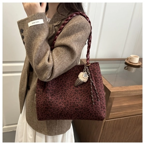 Dettaglio borsa tote bordeaux leopardata con manici intrecciati e ciondolo a gelato
