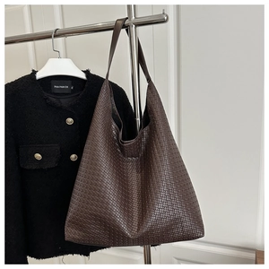 Détail de la texture en cuir tressé marron foncé d'un grand sac cabas avec bandoulière