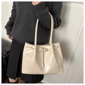 Detail of cream tote bag with knot strap and textured faux leather surface