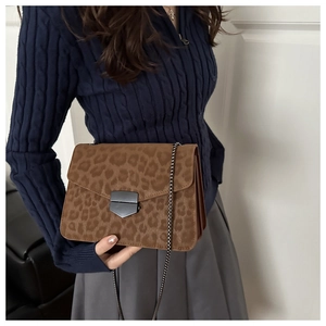 Vue détaillée du sac bandoulière léopard avec chaîne sur un pull en maille bleu