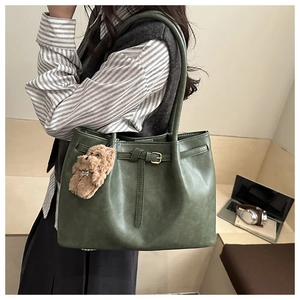 Detail view of a large green tote bag with texture, worn by a model on the shoulder
