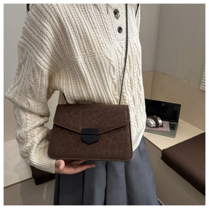 Détail du sac léopard avec boucle en métal noir et bandoulière en chaîne fine
