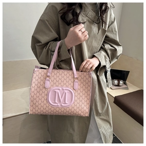 Close-up of pink tote bag with M-letter pattern and embossed logo in a lifestyle setting