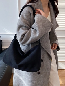 Minimalist black canvas crescent shoulder bag shown on model for daily commuting fashion
