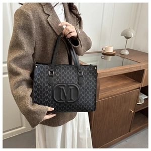 Detail of checkered tote bag with embossed M logo and stylish monogram print patterns