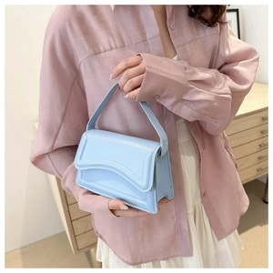 Close-up of a light blue glossy leather handbag with wavy flap detail for women