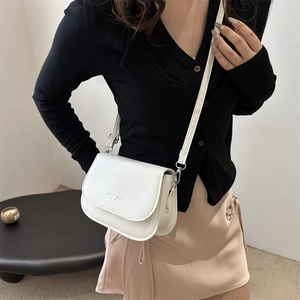 White leather crossbody saddle bag with flap and stamped fashion logo on minimalist model