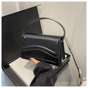 Close-up of black shoulder bag with wavy flap design and elegant leather texture