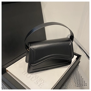 Close-up of black leather underarm bag with unique wavy flap and gold hardware detail