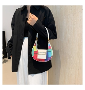 Close-up of geometric rainbow patchwork design and gold crescent buckle on PU shoulder bag