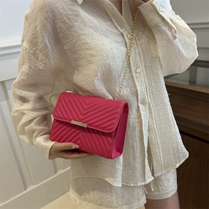 Hot pink quilted crossbody bag with golden chain strap and V-shaped stitching detail