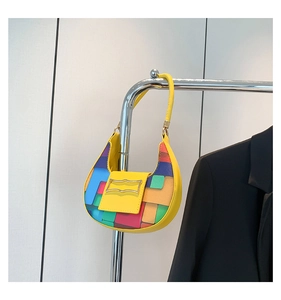 Detail of color-block crescent bag with geometric patches and wavy silver buckle