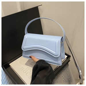 Detail of baby blue flap bag with decorative stitching and solid top handle