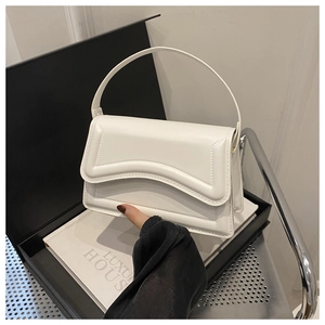 Detail view of cream leather shoulder bag with unique wavy stitching on the flap
