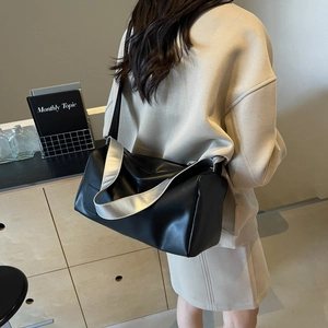 Chic black cylindrical shoulder bag with a wide strap shown from a back side angle
