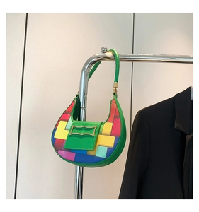 Detail of green crescent bag with colorful pixel patterns and unique gold geometric clasp