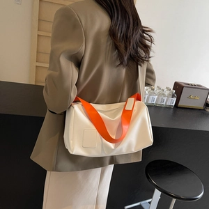 Minimalist white tote bag with bright orange shoulder strap shown on a model