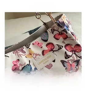 Detail of colorful butterfly prints on white canvas bag with chic golden ring hardware