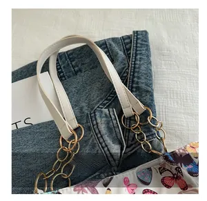 Detail of canvas tote bag showing colorful butterfly prints and gold chain handle