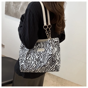 Detail of trendy zebra print tote bag featuring gold chain links and white leather straps