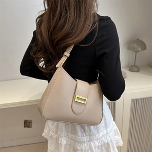 Sac à bandoulière beige minimaliste pour femme avec fermoir doré dans un décor moderne