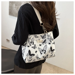 Detail of canvas tote bag with butterfly pattern and decorative gold chain strap