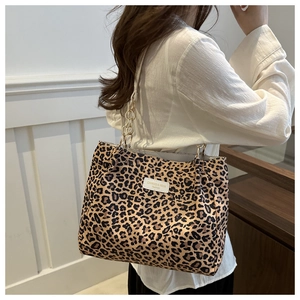Detail of leopard print canvas tote bag featuring chain shoulder strap and logo patch