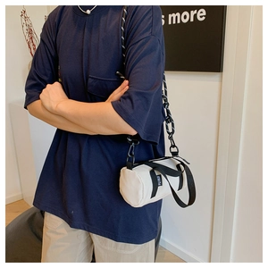 Vue latérale du sac bandoulière cylindrique en nylon beige avec bandoulière noire