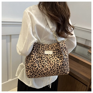 Detail view of large leopard print tote bag with metal chain strap and brand leather patch