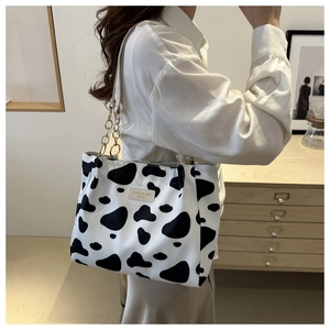 Detail of cow print tote bag with metal chain strap and luxury leather brand label