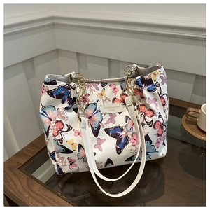 Close-up of a white tote bag featuring colorful butterfly prints and a gold chain strap