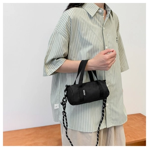 Détail du mini sac cylindre noir avec étiquette FU RUI et bandoulière rayée