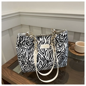 Detailed close-up of zebra pattern tote bag with gold chain and leather handle texture