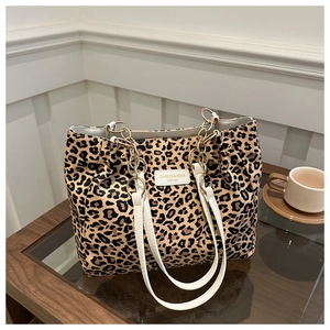 Detail of leopard print tote bag with white shoulder straps and gold chain accents