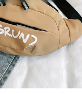 Detailed macro view of khaki nylon chest bag featuring a white RUN print and black zipper