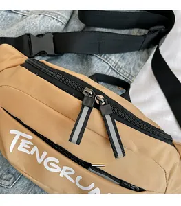 Detail of khaki nylon waist bag with dual zippers, reflective cords and adjustable buckle