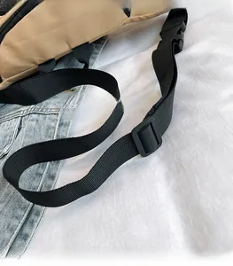 Detail of adjustable black nylon shoulder strap with plastic buckle on khaki canvas bag