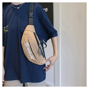 Detail view of khaki waterproof crossbody bag with white logo and dual zip pullers