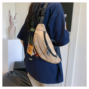 Adjustable wide strap with plastic buckle on a khaki canvas crossbody chest bag