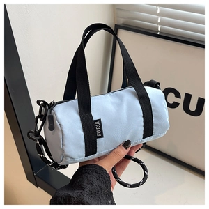 Détail d'un sac cylindrique bleu clair avec chaîne sportive et bandoulière tissée bicolore