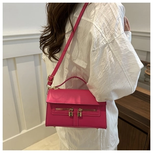 Detail of fuchsia square crossbody bag featuring double metal zippers and golden locks