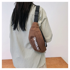 Close-up of brown canvas crossbody bag with white logo and adjustable black strap