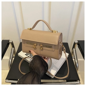 Detail of khaki synthetic leather handbag with golden lock and dual zipper accents