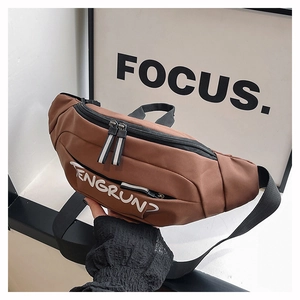 Detailed close-up of a brown oxford chest bag with white lettering and sturdy zippers