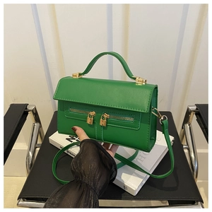 Detailed view of fresh green faux leather handbag with golden hardware locks and top handle