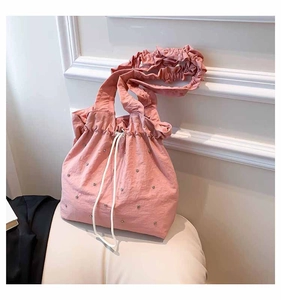 Detail of pink pleated tote bag with drawstring closure and silver rivet accents