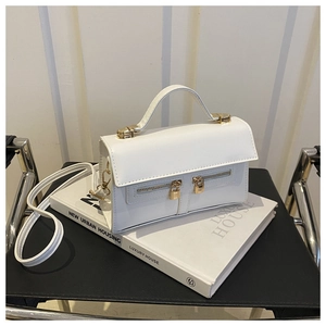 Detailed view of white matte leather handbag with gold zippers and padlock hardware